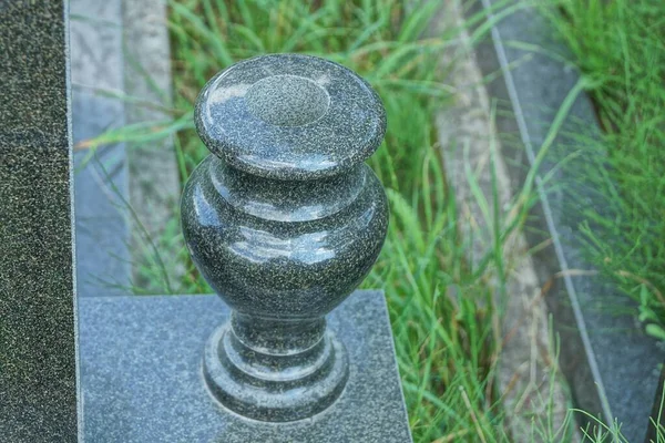 一个巨大的灰色黑色花岗岩花瓶矗立在墓地纪念碑附近的一个灰色大理石石板上 — 图库照片