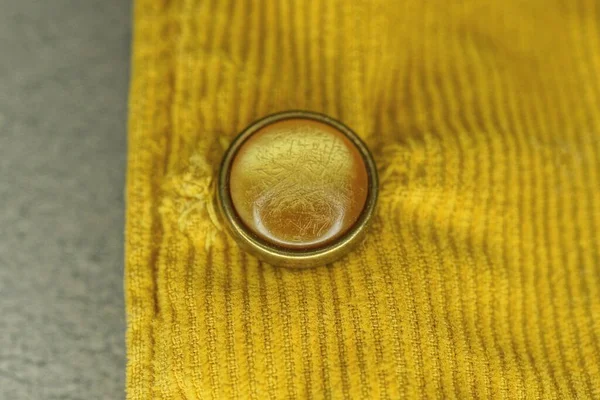 Jeden Kulatý Plastový Knoflík Žluté Látce Oděvu Šedém Stole — Stock fotografie