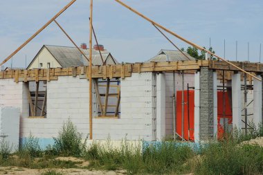 Caddede, mavi gökyüzüne karşı inşaatta olan bitmemiş büyük, özel, beyaz tuğlalı bir ev.