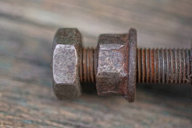 Kahverengi paslı, eski demir cıvata, fındıklı gri ahşap masada yatıyor.