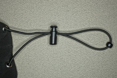 Siyah kumaş eşofmanın bir parçası. Gri masanın üzerinde elastik ve uzun dantelli.