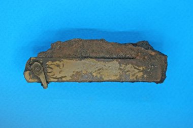 Kahverengi paslı demir bıçaklı eski yeşil bakır bir bıçak mavi bir masanın üzerinde yatıyor.