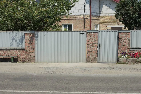 灰色金属门和门 以及街上用褐色石头和铁做的篱笆的一部分 — 图库照片
