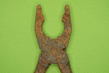 Kahverengi eski demir paslı pense yeşil bir masada yatıyor.