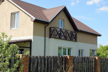 Açık kahverengi ahşap balkon özel bir evin duvarında fayanslı bir çatının altında.