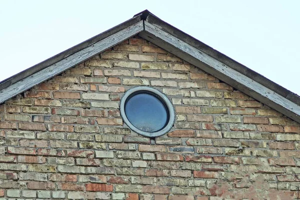 灰色の空に一つの灰色の丸い窓を持つ茶色のレンガのロフト — ストック写真