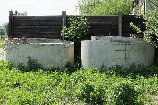 Dwa Szare Betonowe Pierścienie Stoją Zewnątrz Zielonej Trawie Pobliżu Brązowego — Zdjęcie stockowe