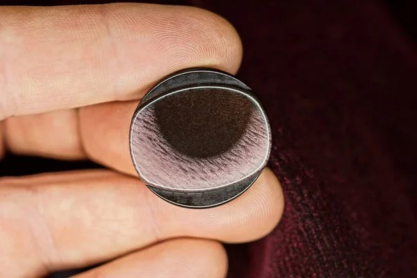 Elin üzerindeki parmaklar elbisenin kumaşında büyük bir plastik kahverengi düğme tutuyor.