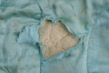 yırtık bir delik ve gri pamuklu kirli mavi kumaştan yapılmış eski bir battaniyenin parçası.