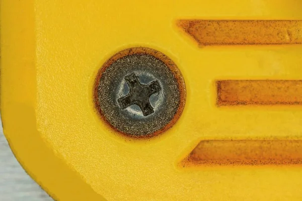 一个黑色铁钉在一个肮脏的黄色塑料墙上的螺栓上 — 图库照片