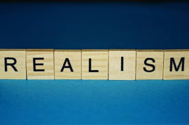 mavi arka planda küçük tahta harflerle gerçekçilik