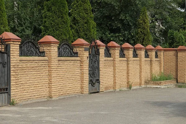 Long Private Brown Brick Fence Wall Black Metal Door Outdoors — стоковое фото