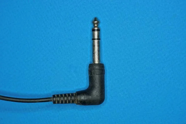 黑色电缆上的一个灰色金属插头躺在一张蓝色桌子上 — 图库照片