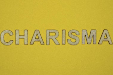 Tahta harflerden yapılmış karizma sarı bir masada yatıyor.