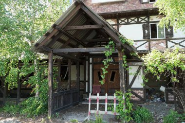 Sokakta terk edilmiş özel bir evin yakınındaki yeşil bitki örtüsünde boş ahşap veranda.