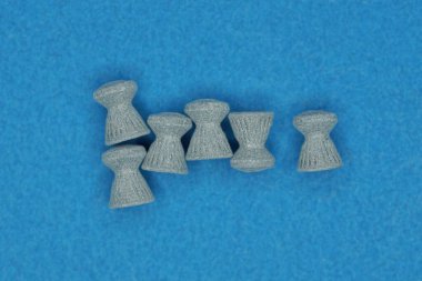 Pnömatikler için küçük gri kurşun mermileri mavi bir masada yatar.