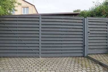 Büyük, gri ahşap bir kapı ve kaldırımdaki kırsal bir sokakta kapalı bir kapı.