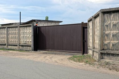 bir kapalı kahverengi metal kapı ve caddedeki gri beton duvarın bir parçası
