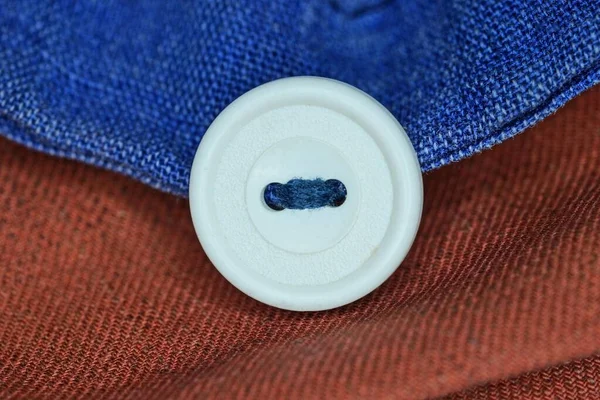 Jeden Duży Biały Plastikowy Przycisk Ubraniu Czerwonego Niebieskiego Materiału — Zdjęcie stockowe