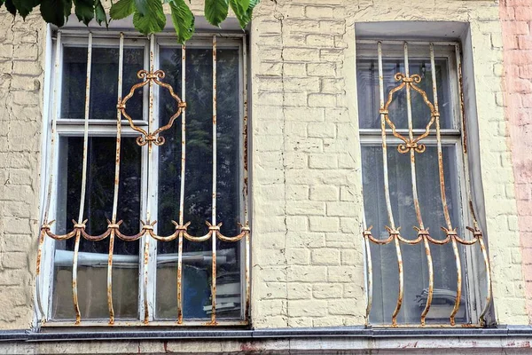 通りの灰色のレンガの壁に鉄格子の後ろに2つの古い窓があり — ストック写真