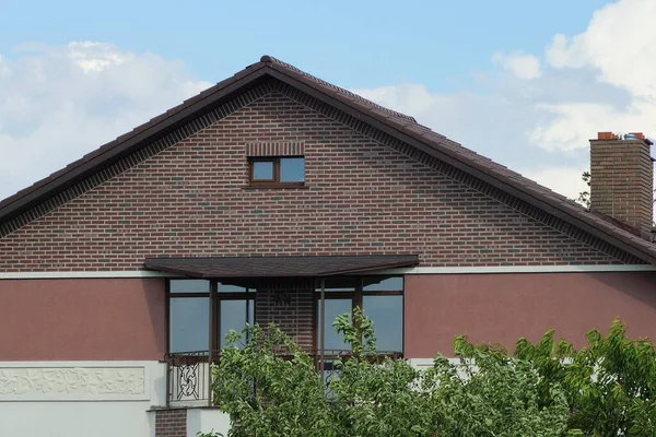 青い空に向かって通りに窓のある鉄のバルコニー付きの民家の茶色のレンガ造りの屋根裏部屋 — ストック写真