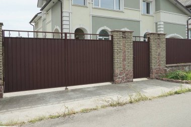 büyük kapalı bir metal kapı ve duvarın bir kısmı sokaktaki tuğlalardan yapılmış.