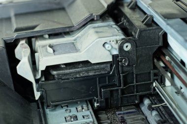 Gri plastik kartuş ve siyah parçaları olan eski bir yazıcının iç mekanizmasının bir parçası.