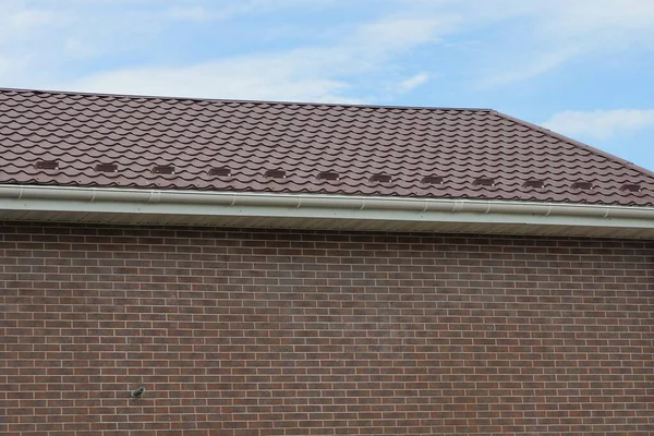 青い空に対してタイル張りの屋根の下の茶色のレンガの壁から大きな家の一部 — ストック写真