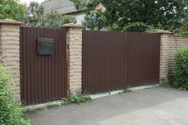 büyük kapalı bir metal kapı ve duvarın bir kısmı yeşil bitkilerle kaplı duvarlardan oluşuyordu.