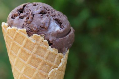 Yeşil arka planda waffle bardağında bir kahverengi dondurma.