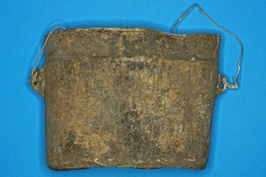 Eski, buruşmuş bir ordu gri alüminyum melon şapkası mavi bir masada yatıyor.