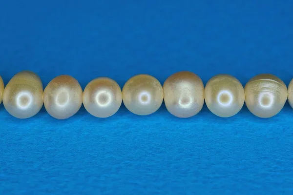 Eine Reihe Grauweißer Perlen Liegt Auf Einem Blauen Tisch — Stockfoto