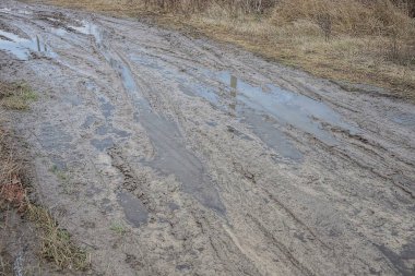 Çamurda kahverengi su birikintileri ve çukurlar yolun ıslak zemininde caddede