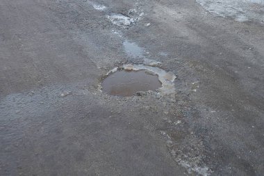 Soğuk bir kış gününde gri asfalt bir yolda buzlu bir çukur.