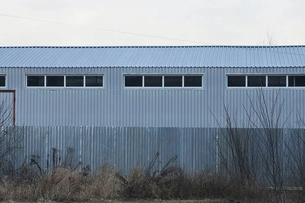 Szary Metalowy Budynek Przemysłowy Małymi Oknami Ulicy Szarej Roślinności Ulicy — Zdjęcie stockowe