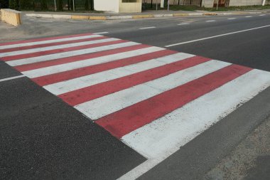 Gri asfalt yolda beyaz çizgili kırmızı yaya geçidi. 