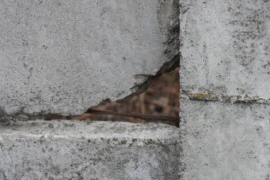 Büyük kahverengi bir deliği olan eski bir beton duvarın gri taş dokusu.