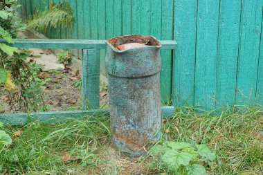 Eski bir paslı metal gaz silindiri dışarıdaki çitin yakınındaki çimlere kazılmış.