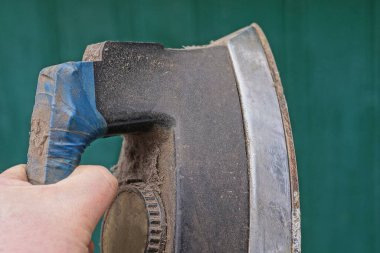 Yeşil arka planda eski bir elektrikli ütüyü tutan el.