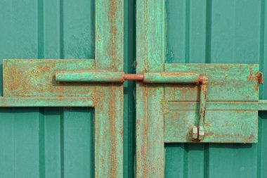 sokağın yeşil metal kapısında büyük bir demir kahverengi paslı sürgü.