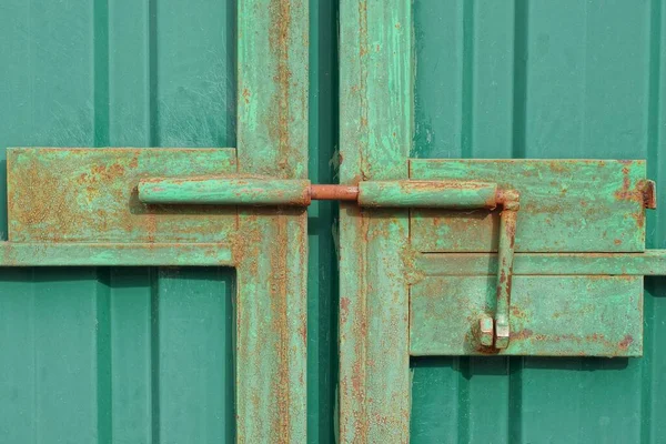 sokağın yeşil metal kapısında büyük bir demir kahverengi paslı sürgü.