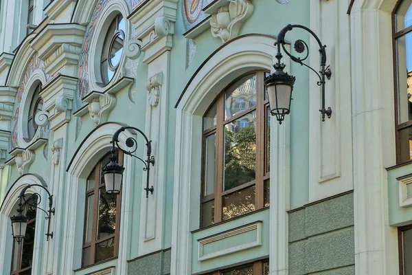 通りに黒い提灯のある古い家の緑の石壁の茶色の窓の列 — ストック写真