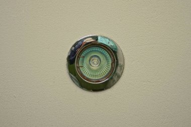 one small gray round led light bulb on the white ceiling in the room