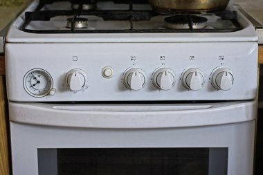 Mutfaktaki odada bulunan beyaz metal gaz sobasının bir parçası.