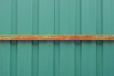 Kahverengi paslı demir plakalı metal bir duvardan yeşil doku.