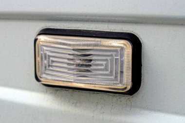 one small white black plastic headlight on a gray dirty metal car