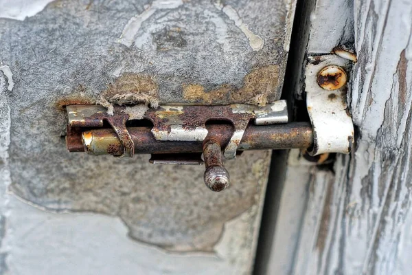 Kapalı eski gri metal bir mandal beyaz ahşap bir kapı üzerinde