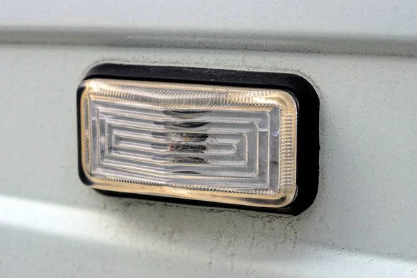 Gri metal bir arabanın üzerinde küçük siyah plastik bir far.