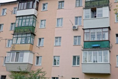 Bir sıra renkli balkon ve caddedeki büyük bir evin kahverengi duvarında bir pencere.