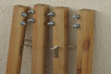 Gri metal fındıklı ve vidalı kahverengi tahta bacaklardan katlanabilir bir masanın ayrıntıları duvara dayanıyor.